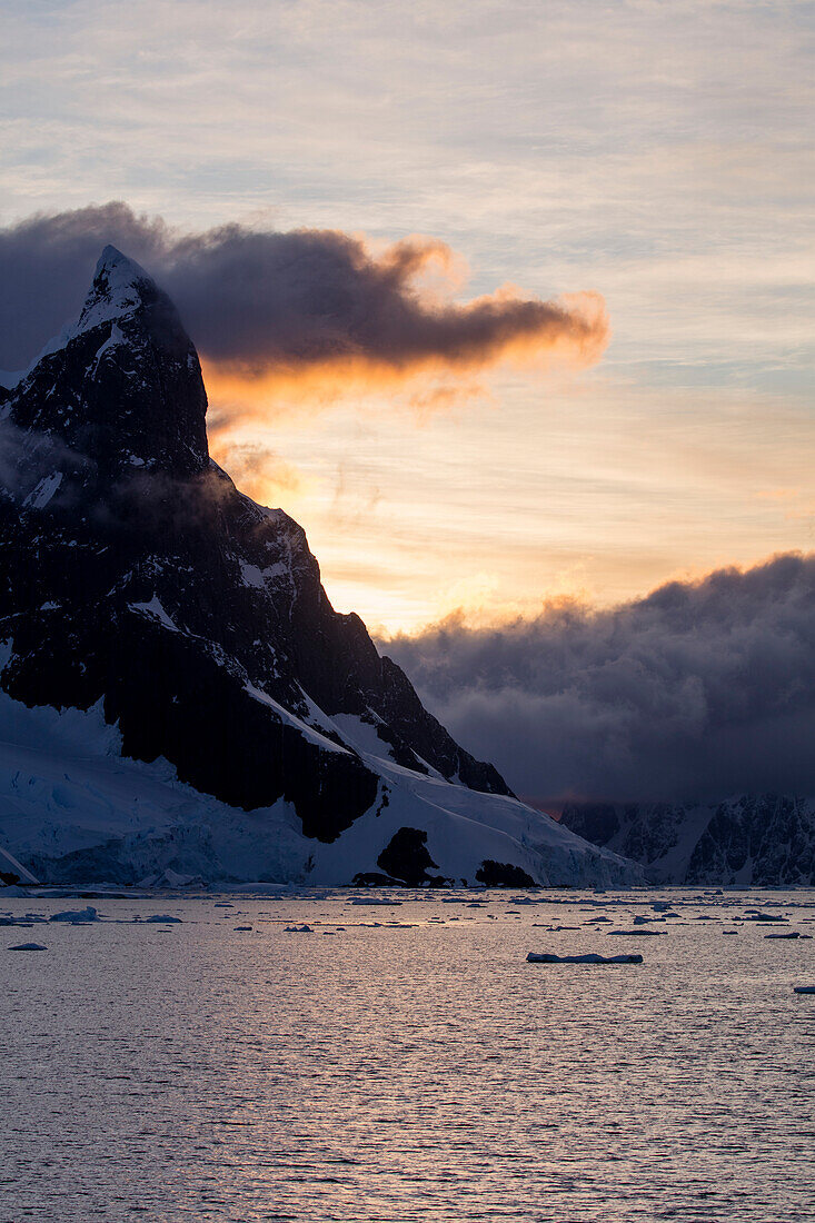 Eisberge und schneebedeckte Berge bei Sonnenuntergang, nahe Lemaire Kanal, Grahamland, Antarktische Halbinsel, Antarktis