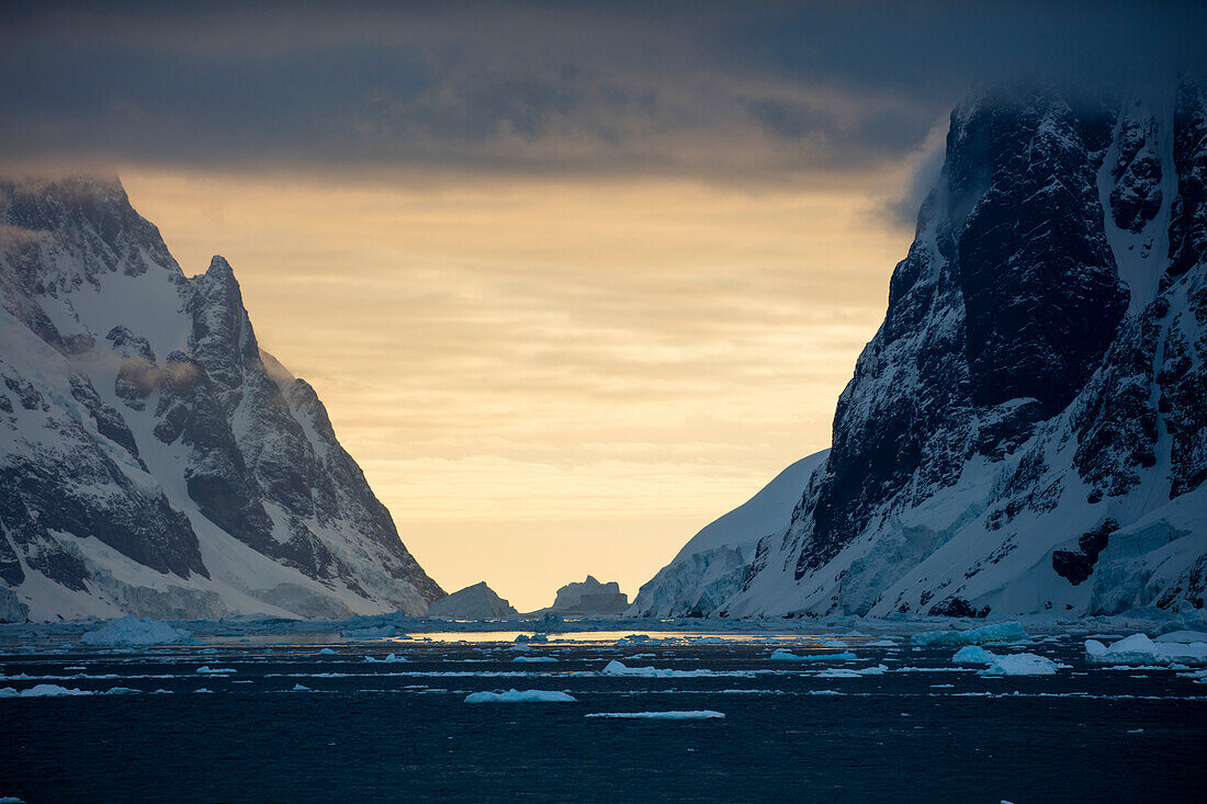 Eisberge und schneebedeckte Berge bei Sonnenuntergang, nahe Lemaire Kanal, Grahamland, Antarktische Halbinsel, Antarktis