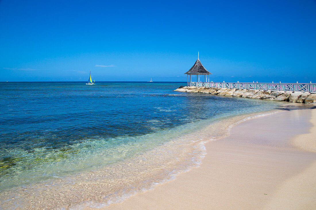 Sunset Beach and jetty with pavilion at Half Moon Resort with Hobie Cat sailboat in Caribbean Sea Rose Hall, near Montego Bay, Saint James, Jamaica