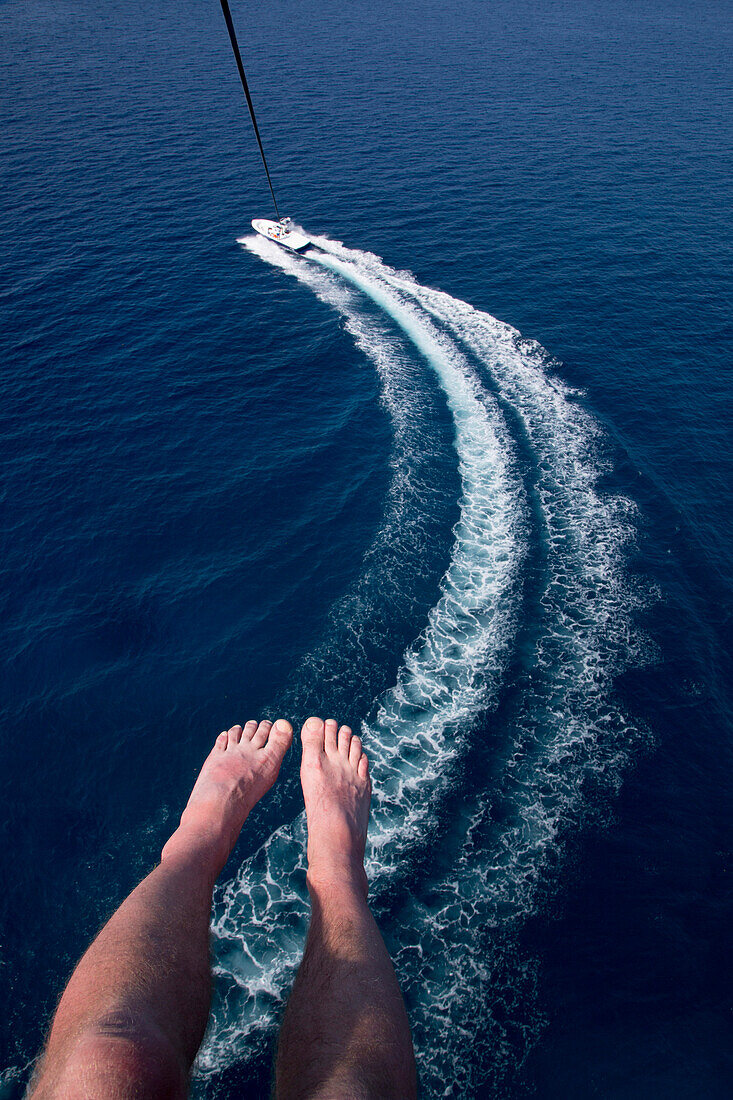 Aerial of photographer's feet and boat wake in Caribbean Sea during parasail activity at Half Moon Resort Rose Hall, near Montego Bay, Saint James, Jamaica