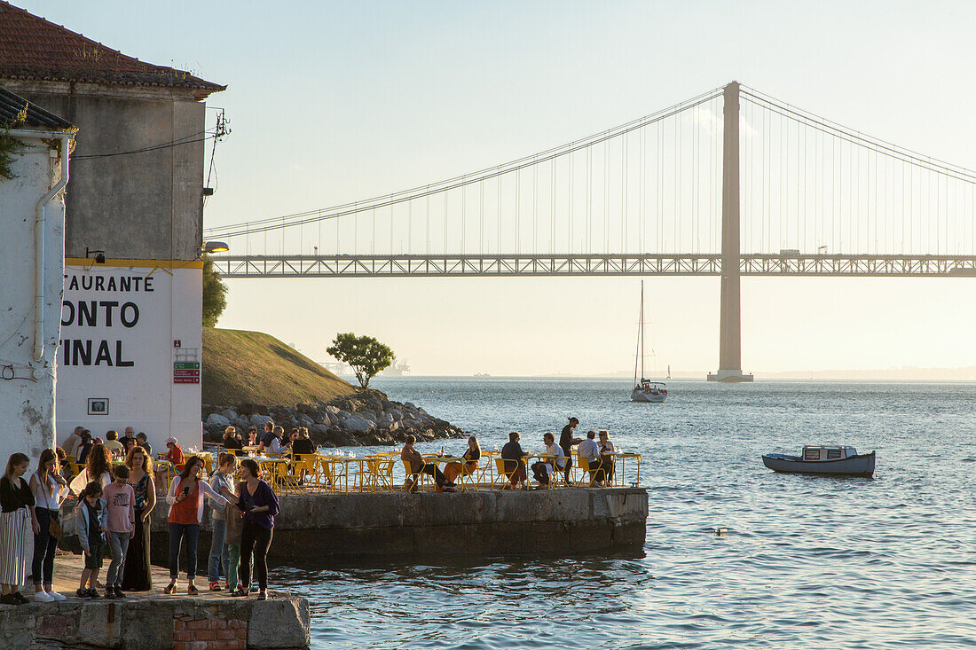 riverfront restaurant Ponto Final, view from south bank of River Tagus,and the 25th April Bridge, Cacilhas, Almada, Lisbon, Portugal