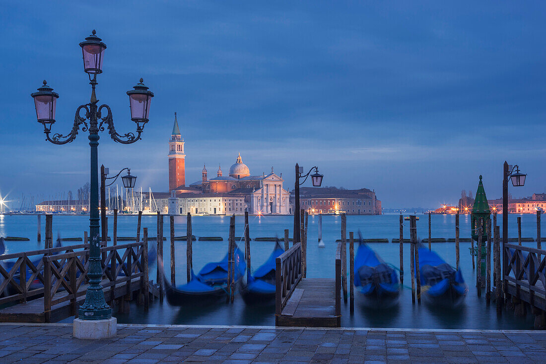View from St. Mark's Square with gondolas and lanterns to the island of San Giorgio Maggiore with its namesake church in the blue of the night, San Marco, Venice, Veneto, Italy