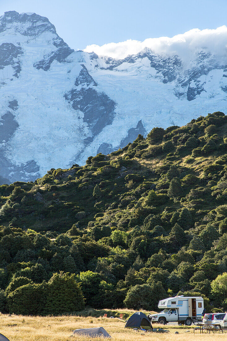 camping beneath alpine scenery, snowy mountains and green forest, White Horse Hill campground, Department of Conservation Doc campground, Mt Cook Nationalpark, South Island, New Zealand