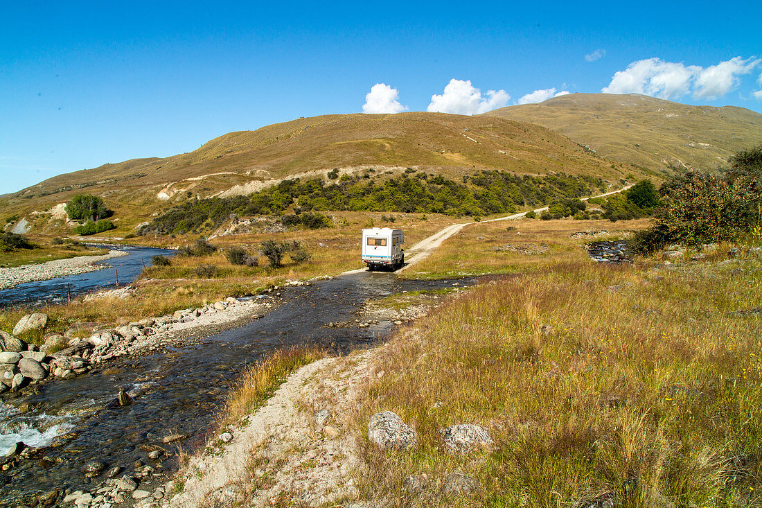 Allrad-Camper überquert Bachlauf im Nevis Tal, Allrad, Piste, höchste öffentliche Straße Neuseelands, Niemand, Tussockgras Landschaft, Central Otago, Südinsel, Neuseeland