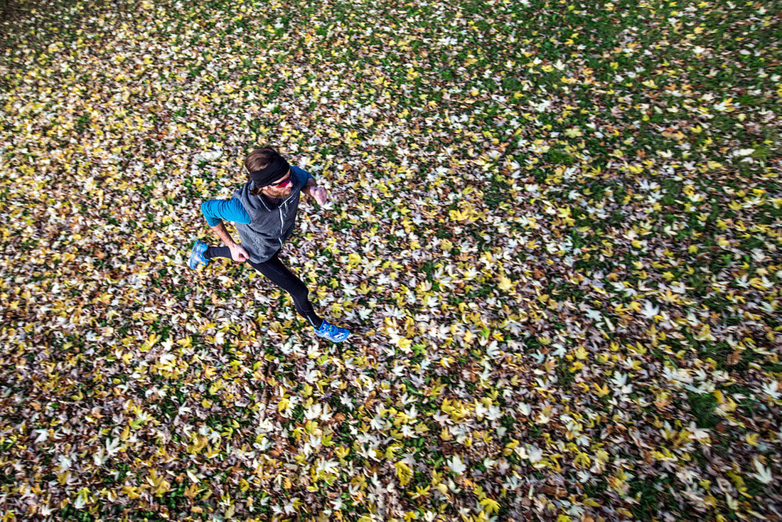 Young man running over a meadow covered in leaves, Allgaeu, Bavaria, Germany