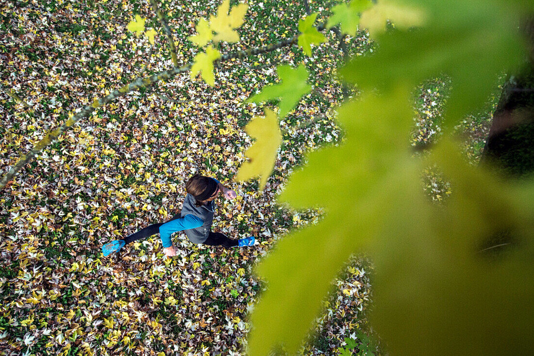 Junger Mann läuft über eine mit Blättern bedeckte Wiese, Allgäu, Bayern, Deutschland