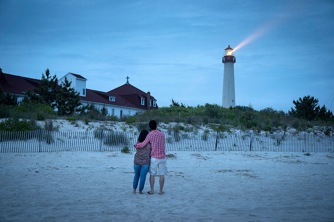 Asian couple watching lighthouse at beach