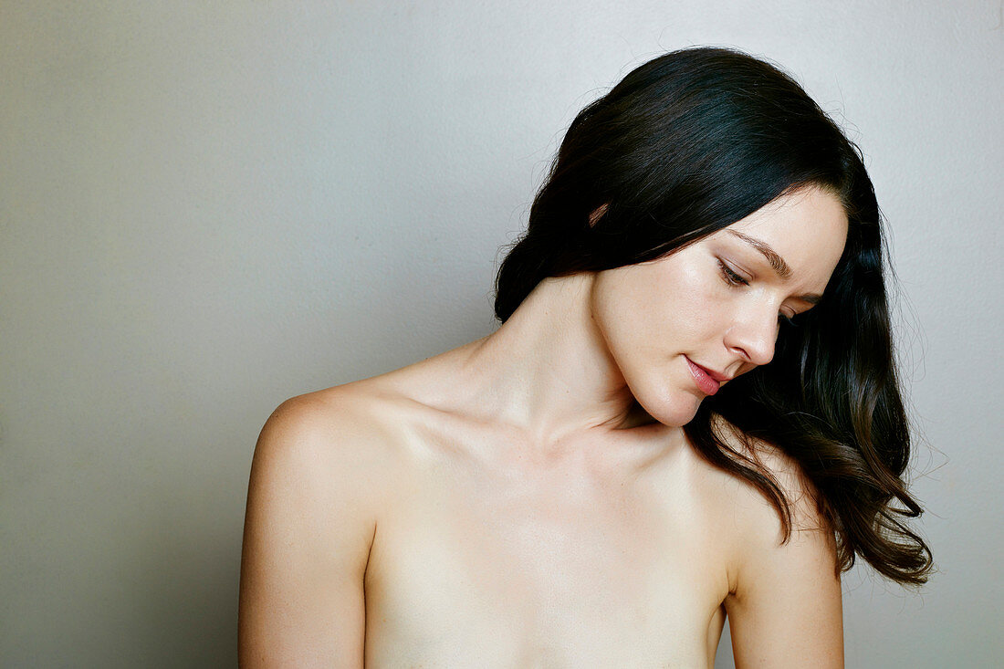 Pensive naked Caucasian woman near wall