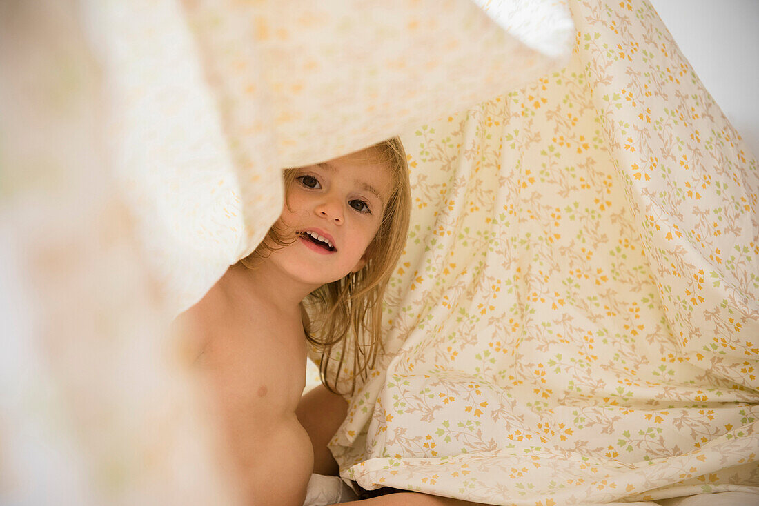 Caucasian girl playing under blankets