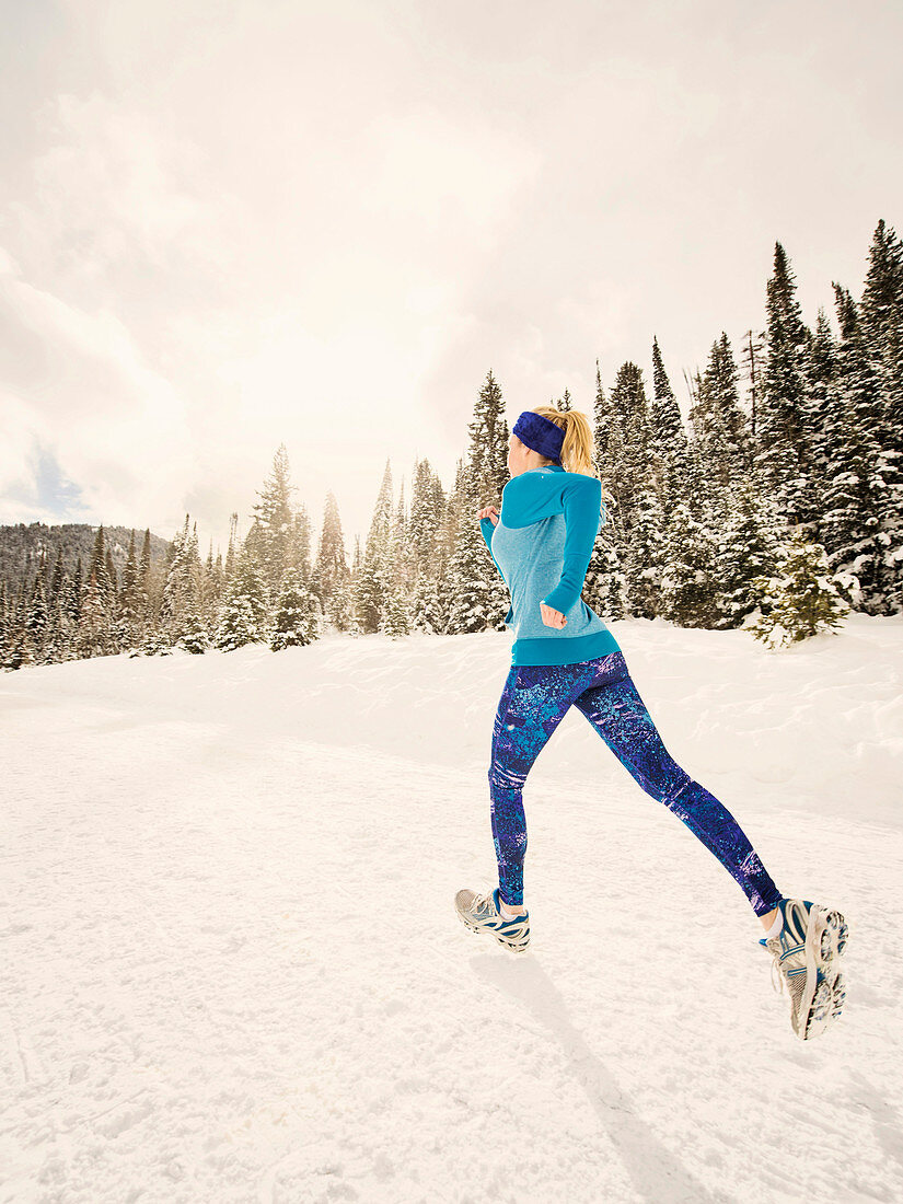 Caucasian woman running in snowy landscape