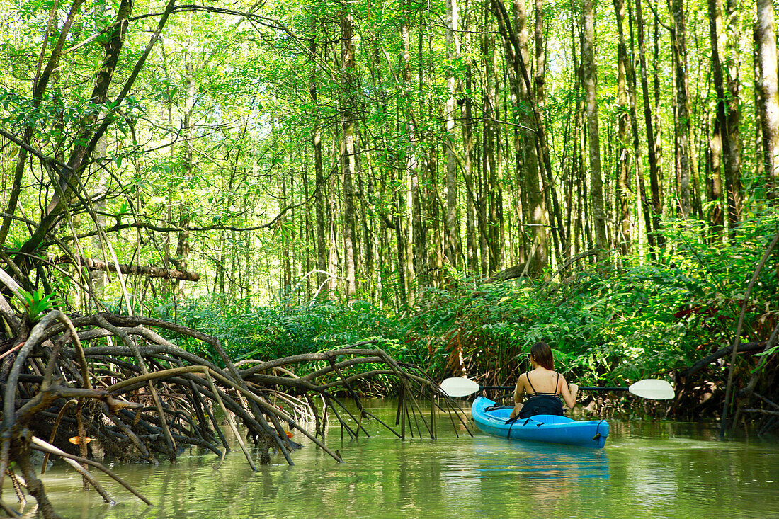 Hispanic woman rowing kayak on river