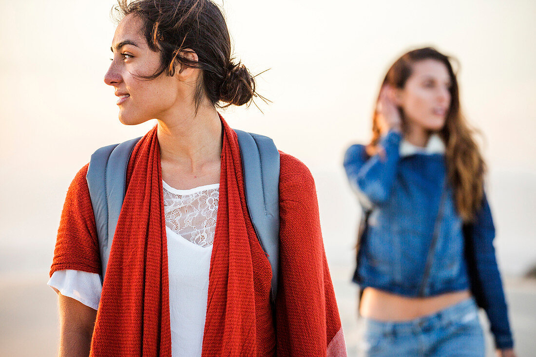 Mixed race women walking on beach