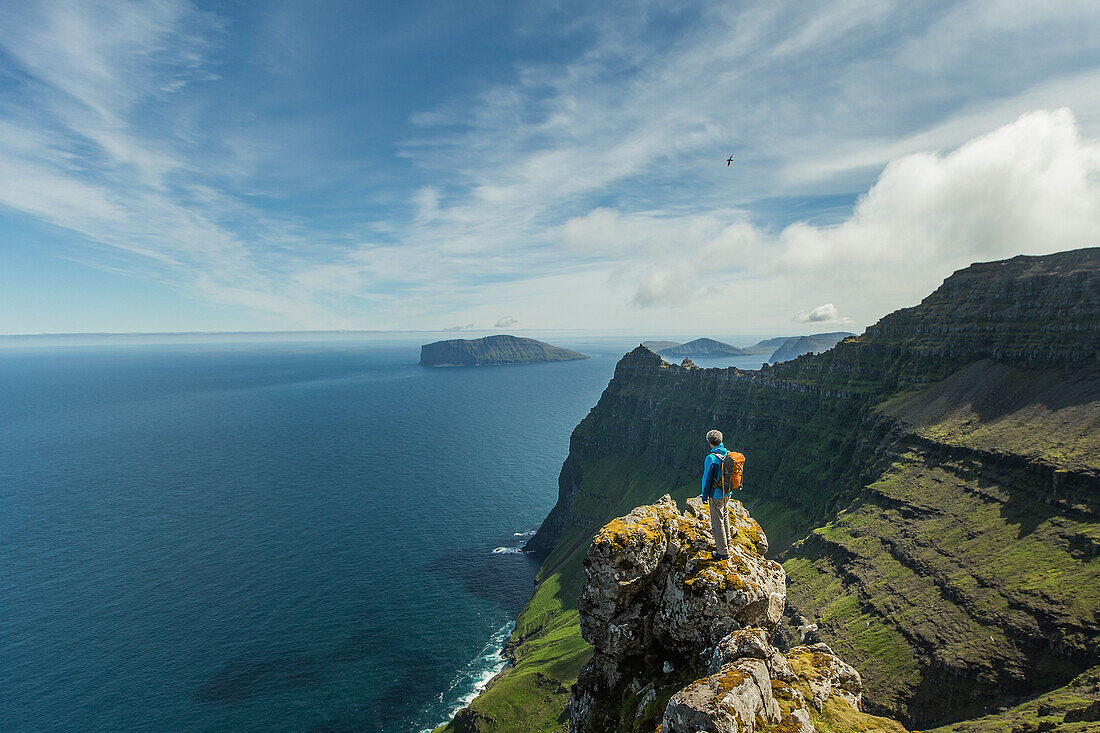 Man standing on the top of a rock in the mountains, Faeroe Islands