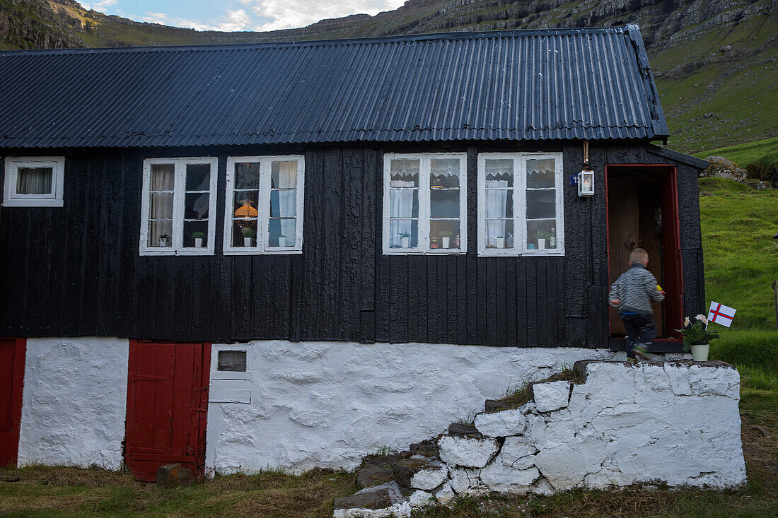 Kleiner Junge läuft in sein Haus, Färöer Inseln