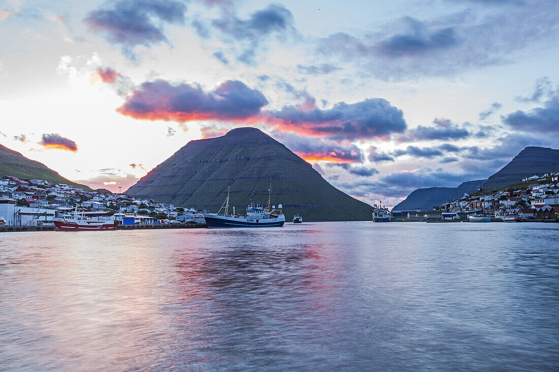 Kleines Fischerdorf umgeben von grün bewachsenen Bergen, Färöer Inseln