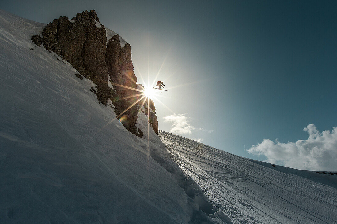 Junger Skifahrer springt eine Klippe in den Bergen herunter, Gudauri, Mzcheta-Mtianeti, Georgien