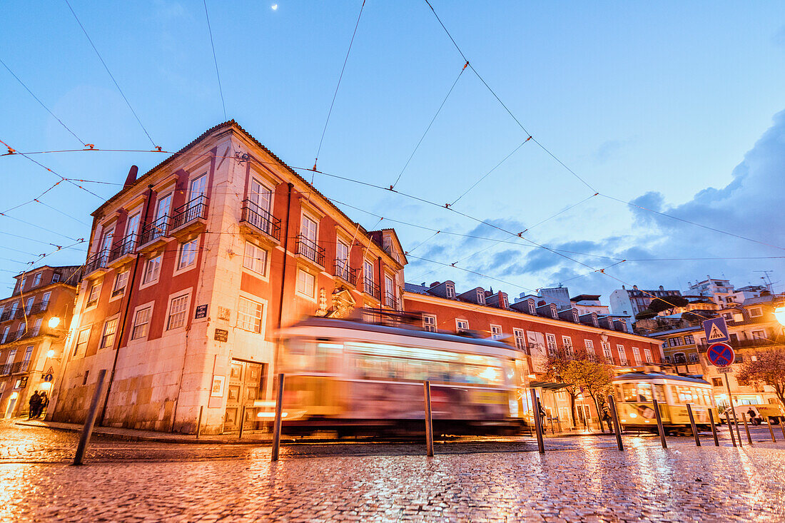 City lights on the typical architecture and old streets at dusk while the tram 28 proceeds, Alfama, Lisbon, Portugal, Europe