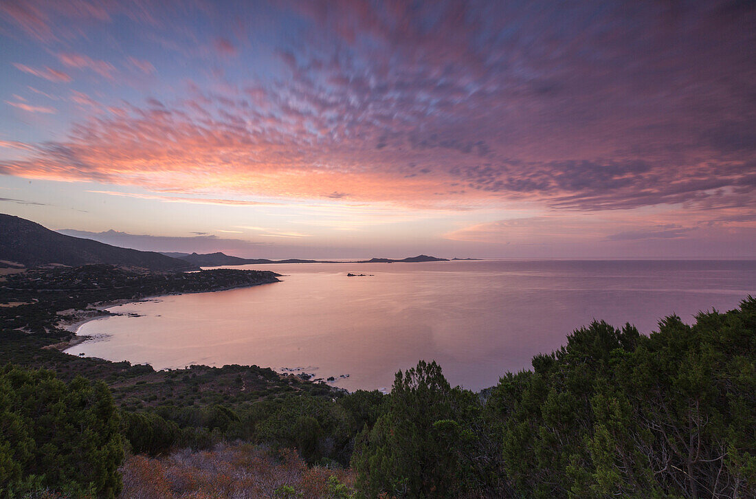 Die Farben des Sonnenaufgangs spiegeln sich auf dem Meer um den Strand von Solanas, Villasimius, Cagliari, Sardinien, Italien, Mittelmeer, Europa