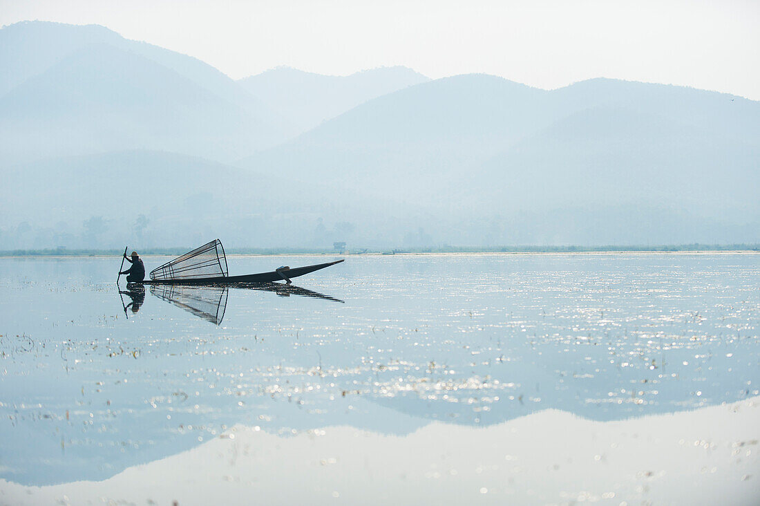 A basket fisherman on Inle Lake scans the still and shallow water for signs of life, Shan State, Myanmar (Burma), Asia
