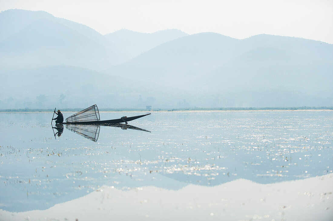 Ein Korbfischer auf Inle See scannt das ruhige und flache Wasser für Zeichen des Lebens, Shan State, Myanmar (Burma), Asien