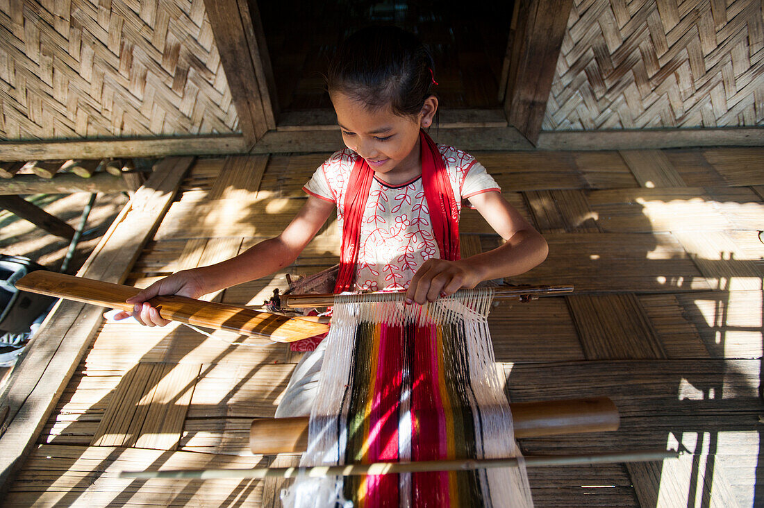 A little girl learns the art of weaving on a hand loom, Chittangong Hill Tracts region, Bangladesh, Asia