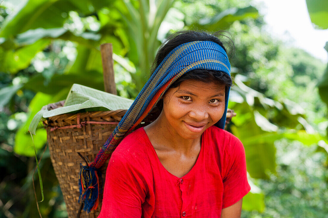 A Chakma girl in the Rangamati area in Bangladesh collects banana flowers which will be used to make curry, Bangladesh, Asia