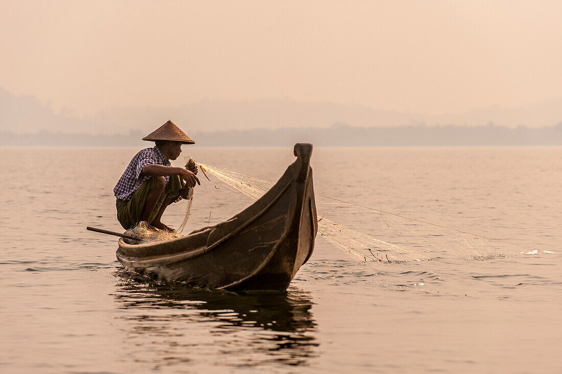 Ein Fischer zieht in seinem Netz auf Indawgyi See in Kachin Staat, Myanmar (Birma), Asien