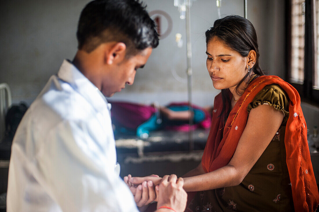 Ein Arzt nimmt den Pulsdruck einer Frau in einem Krankenhaus in Nepal, Asien