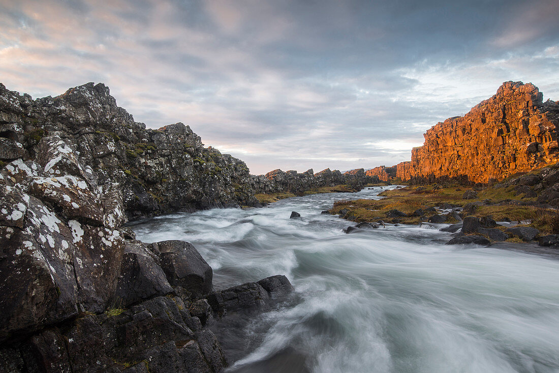 Ein Fluss fließt aus dem Oxarafoss Wasserfall bei Sonnenaufgang im Thingvellir Nationalpark, UNESCO Weltkulturerbe, Island, Polar Regionen