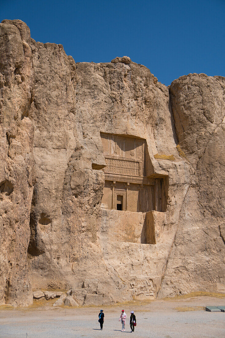 Touristen gehen vor dem Grab von Darius der Große, Naqsh-e Rostam Necropolis, in der Nähe von Persepolis, Iran, Mittlerer Osten