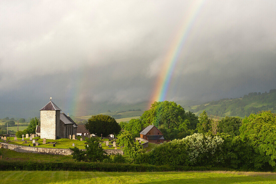 Ein Regenbogen über St. David's Kirche im kleinen walisischen Weiler Llanddewir Cwm, Powys, Wales, Großbritannien, Europa