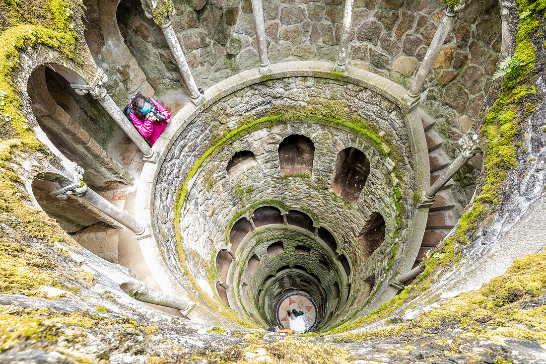 Photographer at the top of the spiral stairs inside the towers of Initiation Well at Quinta da Regaleira, Sintra, Portugal, Europe