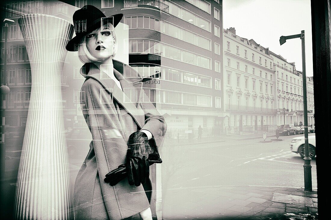 Fashion store, show window. Female mannequin with elegant clothes, hairstyle and make up. Reflections on glass. London, England