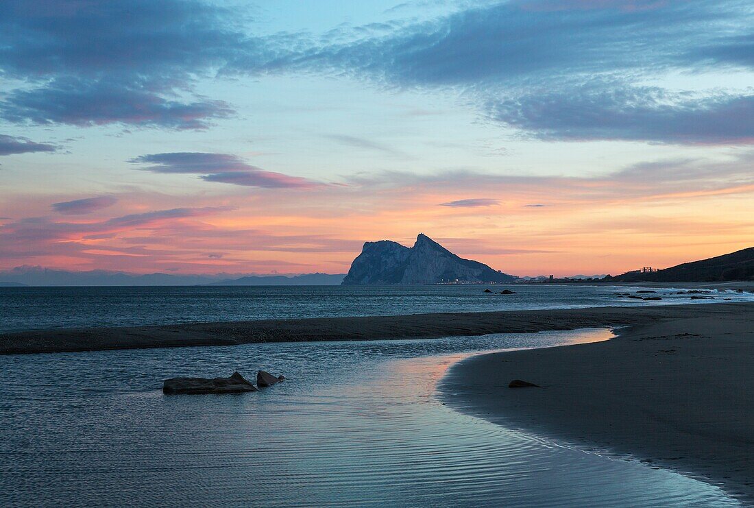 The Rock of Gibraltar (British) seen from the Mediterranean coast north of it. At sunset. Cadiz province, Andalusia, Spain.