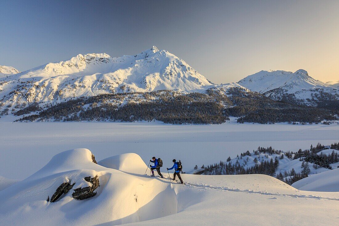 Snowshoe hikers explore the winter landscape in Engadine. Switzerland.