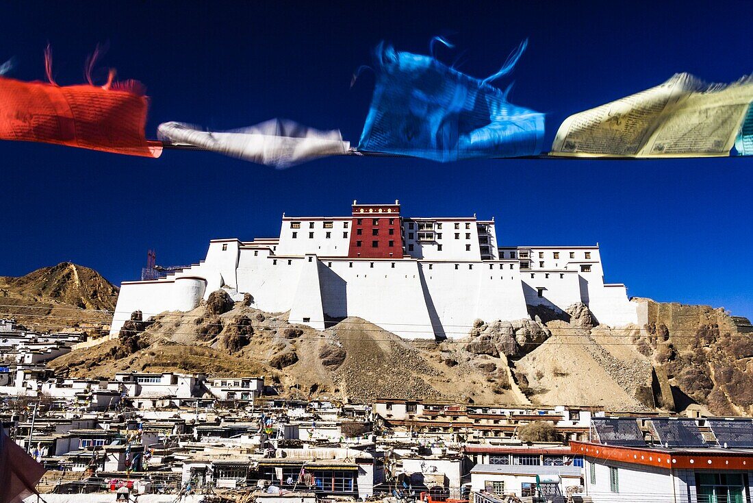 View of the rebuilt Dzong of Shigatse or Samdruptse Dzong with prayer flags in foreground. Shigatse, Tibet.