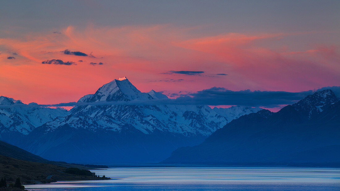 The last rays of the setting sun strike the peak of Aoraki (Mount Cook) beyond the shores of Lake Pukaki in the Southern Alps, UNESCO World Heritage Site, Canterbury, South Island, New Zealand, Pacific