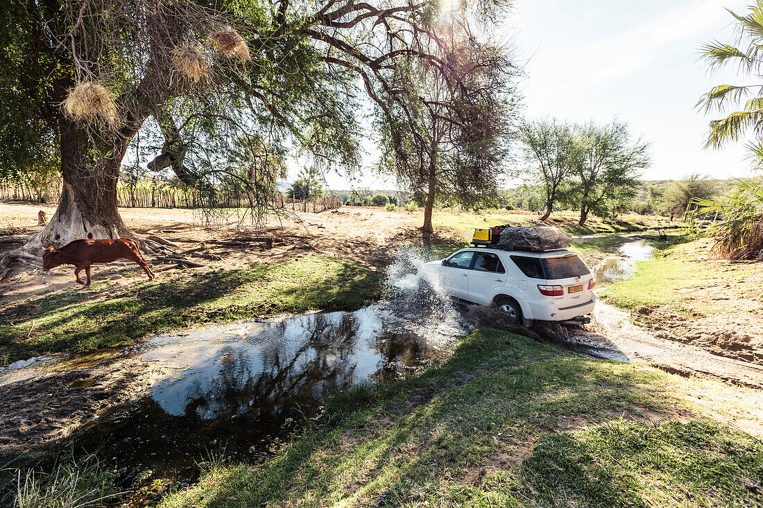 All-terrain vehicle crossing a creek, Kunene, Namibia, Africa