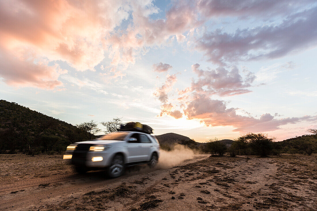 All-terrain vehicle at dusk on a dirt road in Damaraland, Kunene, Namibia