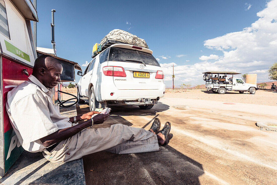Der Tankwart zählt seine Geldscheine, Damaraland, Kunene, Namibia