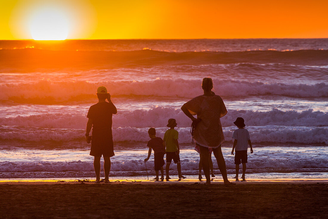 Familie, Kinder, Wellen am Strand, beobachten Sonnenuntergang, Sonne geht im Meer unter, Naturerlebnis, Silhouette, Gegenlicht, Horizont, Westküste, Nordinsel, Neuseeland