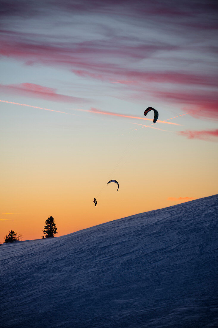 Silhouette von Snowkiter in luftiger Höhe auf der Wasserkuppe im Winter in der Abenddämmerung, nahe Poppenhausen Abtsroda, Rhön, Hessen, Deutschland