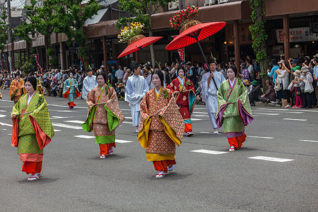 Frauen in traditioneller Kleidung und rotem Schirm während des Aoi Matsuri in Kyoto, Japan