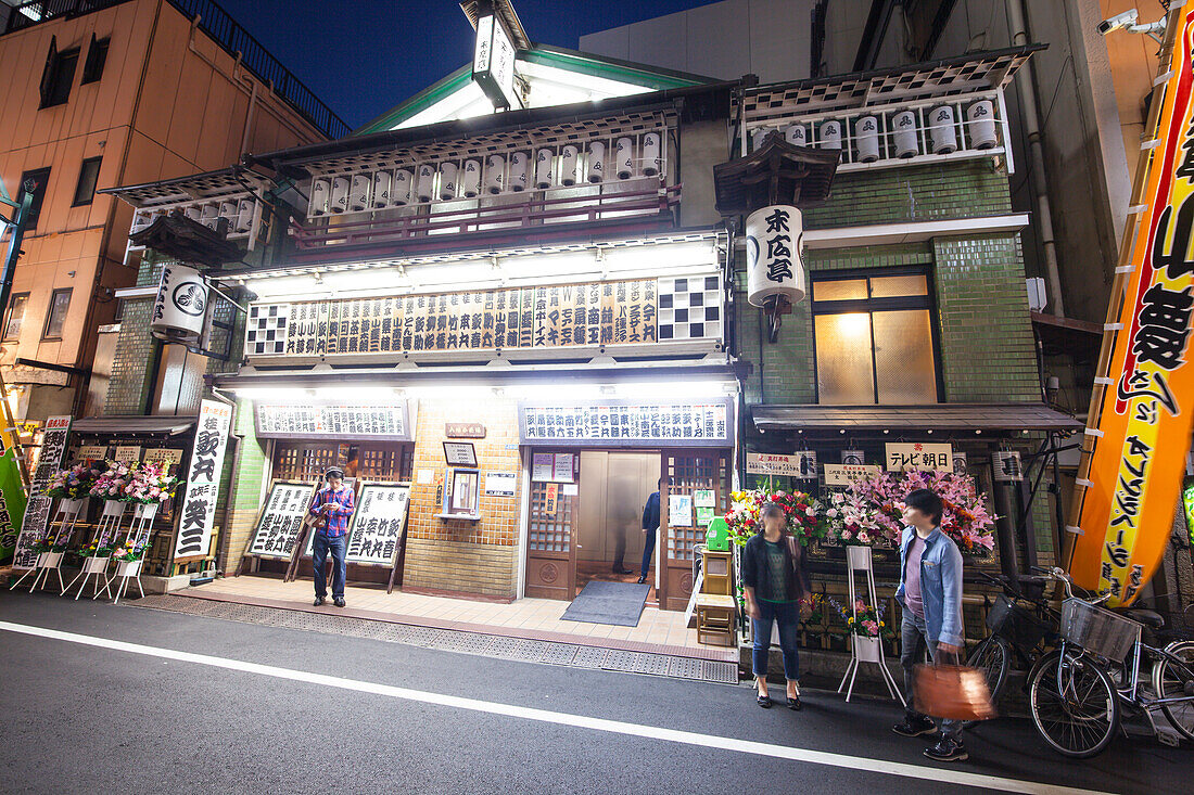 People waiting in front of Shinjuku Suehirotei at night, Shinjuku, Tokyo, Japan