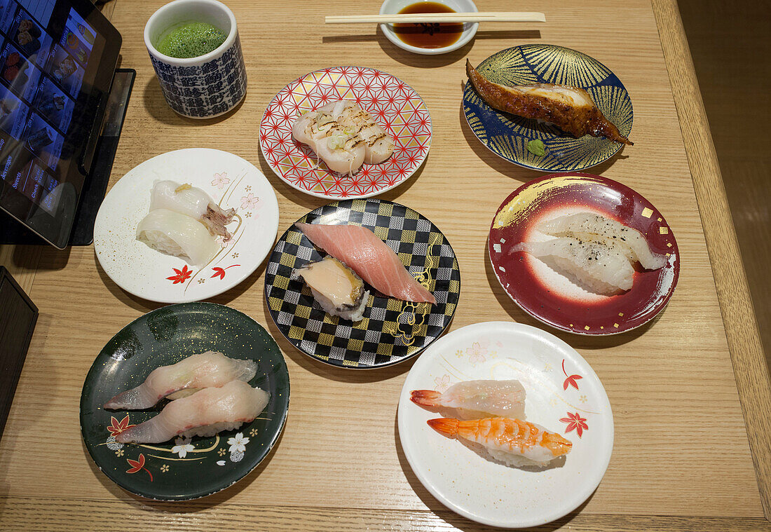 Auswahl an Tellern mit Nigiri-Sushi in einem Kaiten-Sushi-Restaurant, Shibuya, Tokio, Japan