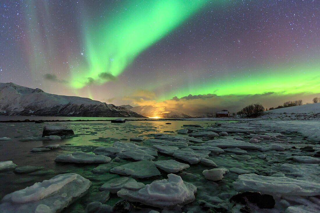 The Northern Lights illuminates the icy landscape in Svensby Lyngen Alps Tromsø Lapland Norway Europe.