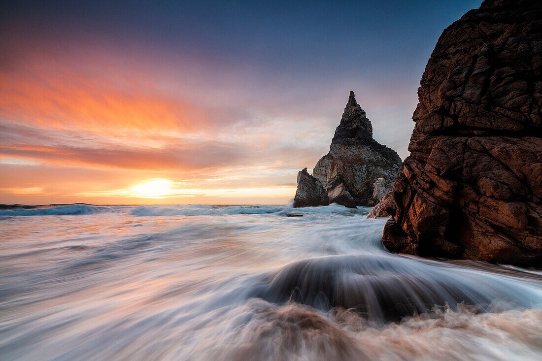 The fiery sky at sunset is reflected on the ocean waves and cliffs Praia da Ursa Cabo da Roca Colares Sintra Portugal Europe.