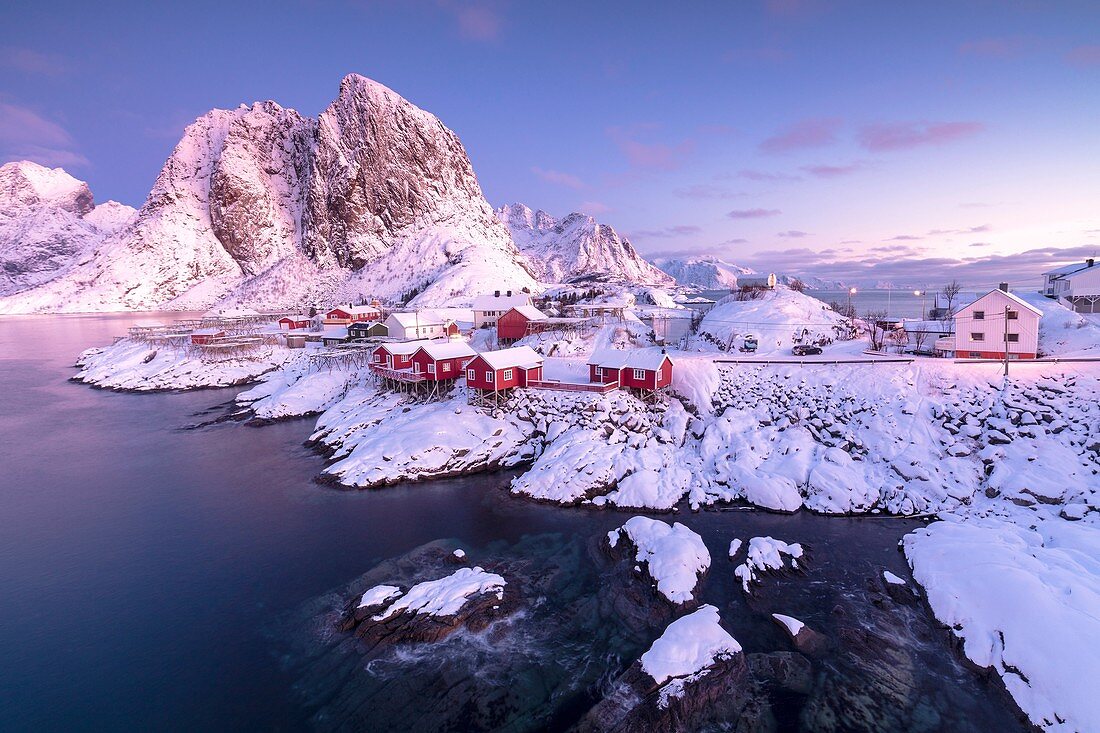 Pink sunrise on snowy peaks surrounded by the frozen sea around the village of Hamnoy Nordland Lofoten Islands Norway Europe.
