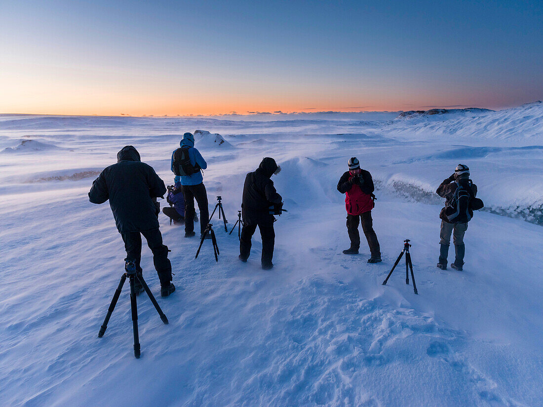 Photographers at sunrise and in a winter storm on the glacier Breithamerkurjoekull in the Vatnajoekull NP. europe, northern europe, iceland, February.