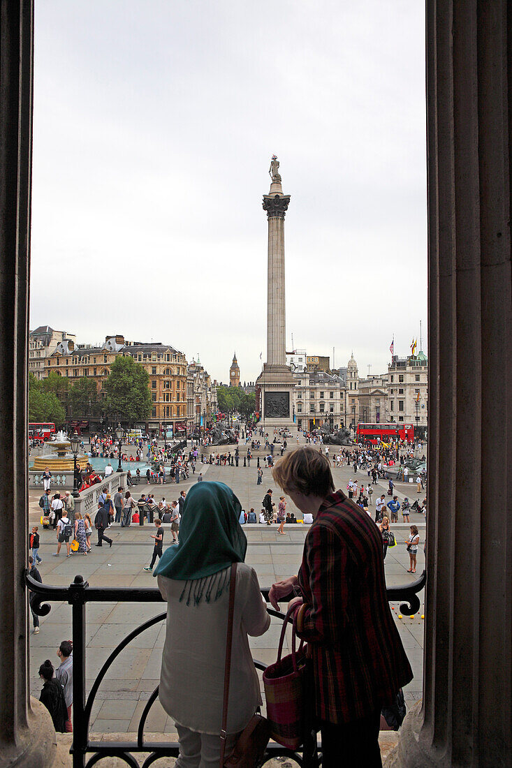 Paar blickt von der Terrasse der National Gallery auf das Treiben des Trafalgar Square, dahinter Whitehall und Big Ben, London, England